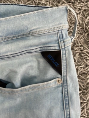 Ljusblå raka jeans från Replay - Säljer ett par ljusblå jeans från Replay med raka ben och klassisk femficksmodell. Jeansen har en snygg tvättad look och detaljer i silverfärgad metall. Materialet är mjukt denim som känns bekvämt hela dagen.