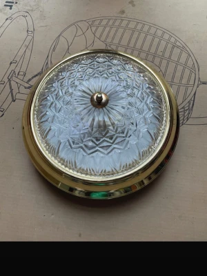 Rund taklampa i glas - Säljer en rund taklampa med dekorativt slipat glas och ram i blank mässing. Lampan har ett klassiskt mönster i glaset och en liten knopp i mitten. Perfekt för dig som vill ha en elegant och tidlös belysning till hemmet.