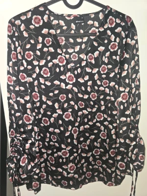 Blommig svart blus med långa ärmar - Snygg svart blus från Gina Tricot med rosa och vita blommor över hela tyget. Det går att justera armlängden. Storlek: 36. Katt finns i hemmet! Hör av dig om du har frågor eller vill ha fler bilder! ✨