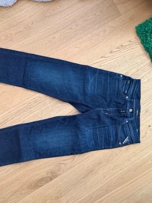 Mörkblå Replay Jeans - Snygga mörkblå jeans i slim fit-modell med klassisk femficksdesign och diskreta slitningar framtill. Jeansen har normal midja och raka ben. Jag har använt dem 1 eller 2 gånger. Helt nytt skick.