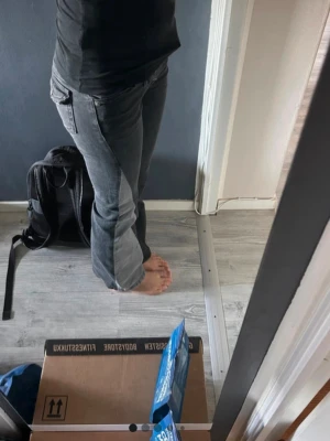Grå bootcut jeans med fickdetaljer - Säljer ett par grå bootcut jeans med snygga sömmar och dekorativa knappar på bakfickorna. Jeansen har klassisk femficksdesign och är tillverkade i ett stretchigt denimtyg som sitter bekvämt. Perfekta för en avslappnad och trendig look.