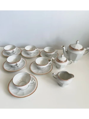 Krüger - Vitt porslinskaffeset med guldkant - 15 delar - Supersöt liten kaffeservis från anrika keramiktillverkaren EK Krüger i vitt porslin med guldfärgade och röda detaljer. Servisen inkluderar 6 kaffekoppar, 6 fat, en kaffekanna, en sockerskål och en gräddkanna. Kopparna är 6 cm i diameter och 4 cm höga, faten har en diameter på 11 cm. Kaffekannan är 9 cm hög, sockerskålen är 6 cm hög och gräddkannan är 5 cm hög. 15 delars set som passar till ljuva små kaffe- eller testunder. Fint skick!