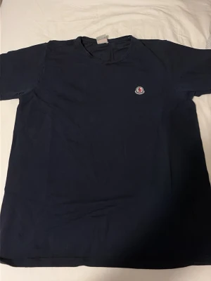 Mörkblå Moncler t-shirt i bomull - Snygg mörkblå t-shirt från Moncler med klassisk rund hals och liten Moncler-logga på bröstet. Tillverkad i mjuk bomull som känns skön mot huden. Perfekt till jeans eller shorts för en clean och enkel stil. Hör av dig vid dm för frågor 💪💪