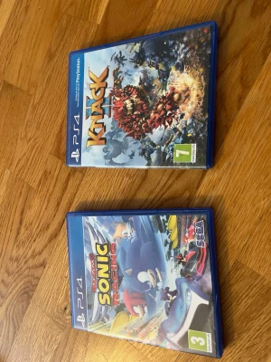 PS4 spel: Knack & Team Sonic Racing - Två PlayStation 4-spel i blå plastfodral: Knack, ett actionäventyr med färgstark grafik och coola strider, samt Team Sonic Racing, ett fartfyllt racingspel med Sonic och hans vänner. Perfekt för dig som gillar äventyr och racing på PS4.
