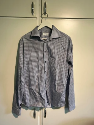 Eton skjorta Rutig - Säljer en stilren skjorta från Eton i modellen Super Slim Fit. Vit med mörkblått småmönster – passar lika bra till kostym som till chinos eller jeans.  * Märke: Eton * Modell: Super Slim * Storlek: 41 / 16 ( motsvarar Large) * Färg: Vit med mörkblått mönster * Skick: Fint begagnat skick, utan hål eller fläckar. * Nytvättad och redo att användas.  Nypris ca 1900kr köpt för 6 månader sedan, säljer p.g.a börjar bli för liten för mig  Pris går att diskuteras 👍