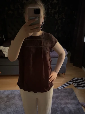 Svart blus med spetsdetaljer - Säljer en svart blus med korta ärmar och fina spetsdetaljer vid axlar och ärmslut. Blusen har en avslappnad passform och är perfekt för dig som gillar en enkel men söt stil.