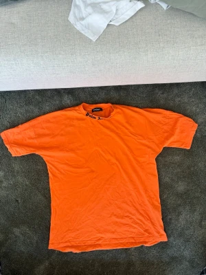 3 olika Palm Angels t-Shirts - Säljer en orange t-shirt från Palm Angels med stor svart logga på ryggen och mindre text vid halsen fram. Oversized passform och klassisk rund hals. Perfekt för dig som vill sticka ut med streetwear-vibe. Olika storlekar men passar rätt så lika