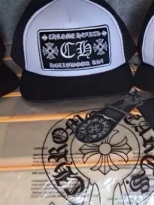 Svartvit truckerkeps Chrome Hearts - Säljer en svartvit truckerkeps från Chrome Hearts med tydlig logga och texten 'Hollywood USA' framtill. Kepsen har mesh på sidorna och bak, samt böjd skärm. Klassisk patch framtill med gotisk stil och korsdetaljer.