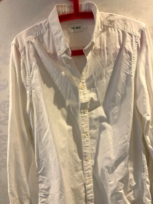 Vit skjorta från East West - Klassisk vit skjorta från East West i storlek S. Skjortan har lång ärm, knappar framtill och en tidlös design som passar till många olika stilar. Tillverkad i mjuk bomull för en bekväm känsla hela dagen.