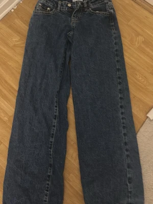 Blå loose fit jeans, storlek 32 - Säljer ett par blå loose fit jeans med hög midja och raka ben. Jeansen har klassisk femficksdesign, dragkedja och knapp i midjan. Materialet är kraftig denim i bomull. Perfekta för en avslappnad och trendig look.