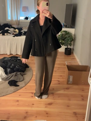 Kort svart dubbelknäppt rock - Säljer en jätte fin kappa ifrån stradivarius, den är väl använder inga tecken på det 