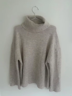 Stickad Beige/ Creme vit polotröja  - Beige/Creme vit oversized stickad polotröja med bred ribbad krage, ärmslut och nederkant. Köpt från Ginatricot och bara använd ett fåtal gånger, inga tecken på användning.