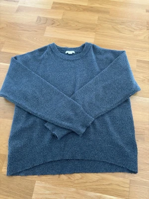 Blå stickad tröja från Gina Tricot - Mysig blå stickad tröja från Gina Tricot med rund halsringning och ribbade muddar vid ärmslut och nederkant. Tröjan har en avslappnad passform och är perfekt för kyliga dagar. Materialet känns mjukt och bekvämt mot huden. 