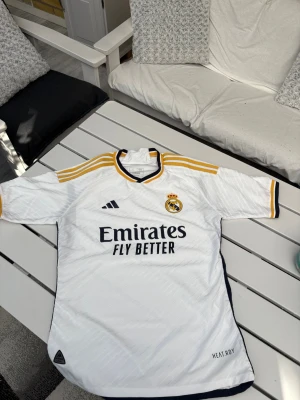 Vit Real Madrid matchtröja - Säljer denna vita Real Madrid matchtröja från Adidas. Tröjan säljs då den var lite för stor för mig. Den är i nyskick oanvänd. Storlek L skriv vid frågor!