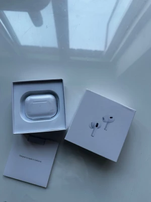 AirPods Pro - Säljer ett par vita Apple AirPods Pro med trådlöst laddningsetui. Snygg och kompakt design med silikonpluggar för bra passform och brusreducering. Levereras i originalförpackning med tillhörande manual.