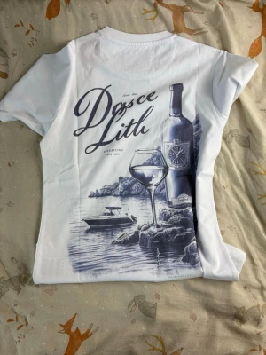 Vit t-shirt från Leon Marcel - Helt ny snygg vit t-shirt från Leon Marcel med diskret tryck 'Marcel' i marinblått på bröstet. Klassisk rund halsringning och korta ärmar. Tillverkad i mjuk bomull som känns skön mot huden. Perfekt för en clean och stilren look.