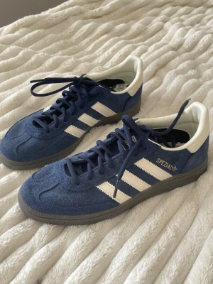 Adidas Spezial blå sneakers - Säljer ett par Adidas Spezial Unisex sneakers i blå mocka med vita detaljer. Endast testade inomhus! Ett år vita skosnören följer med. !!Har ej original skokartong kvar!!