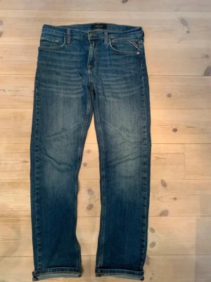 Blå jeans från Replay - Snygga blå jeans från Replay med klassisk femficksdesign och diskreta slitningar. Jeansen har raka ben och normal midja, samt detaljerad söm vid fickorna. Perfekta för en avslappnad och trendig look. Skitsnygga