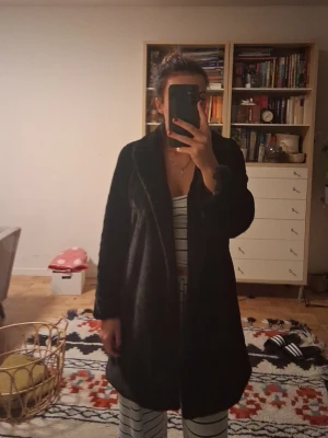 Svart pälsjacka från Boohoo - Säljer en svart pälsjacka från Boohoo i storlek 38. Jackan har en klassisk krage och är helsvart med mjuk pälsimitation på utsidan och slätt foder på insidan. Perfekt för dig som vill ha en snygg och varm look under kallare dagar. Helt oanvänd och tar endast plats så vill bli av med den. Perfekt för utgång.