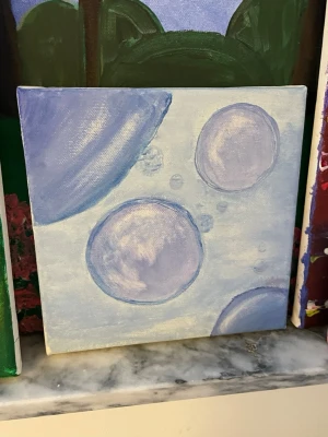 Abstrakt tavla med lila bubblor - Unik handmålad tavla med abstrakt motiv av lila och blå bubblor på ljus bakgrund. Målningen är gjord på en kvadratisk canvas och har mjuka, drömlika färgövergångar. Perfekt som dekoration för att ge rummet en kreativ touch.
