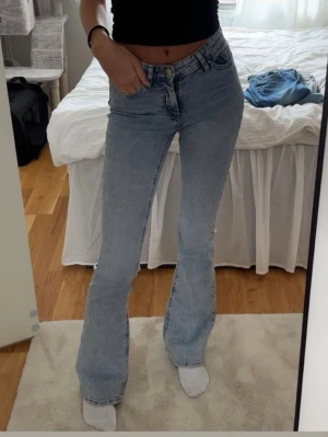 Ljusblå bootcut jeans - Säljer ett par ljusblå bootcut jeans med hög midja och klassisk femficksdesign. Jeansen har en snygg tvätt och är tillverkade i ett stretchigt denimtyg som sitter bekvämt. Aldrig använda så jätte fint skick Xs/34