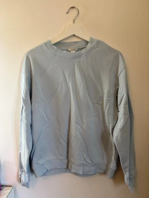 Ljusblå sweatshirt från Monkl  - En enkel och stilren ljusblå sweatshirt från Monkl. Tröjan har rund halsringning, långa ärmar och ribbade muddar vid ärmslut och nederkant. Perfekt för en avslappnad look och lätt att matcha med jeans eller kjol.