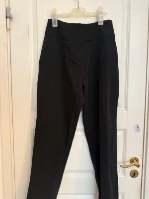 Svarta höga leggings med bred linning - Snygga svarta leggings med hög midja och bred linning som ger en smickrande siluett. Tillverkade i ett stretchigt material som sitter bekvämt och följsamt. Perfekta att matcha med oversized tröjor eller crop tops för en trendig look.