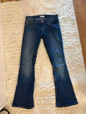 Lowrise jeans Gina Tricot - Snygga blå bootcut jeans från Gina Tricot med klassisk femficksmodell och normal midja. Jeansen har en lätt tvättad look och är tillverkade i ett mjukt denimtyg som sitter skönt. Perfekta för dig som gillar en avslappnad men trendig stil.