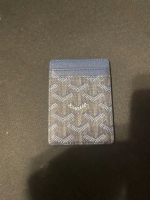 Mörkblå kortfodral från  - Snyggt mörkblått kortfodral   med det klassiska mönstret i vitt och grått. Fodralet har flera kortfack och är tillverkat i canvas med läderdetaljer. Perfekt för dig som vill ha ett stilrent och smidigt sätt att bära dina kort.