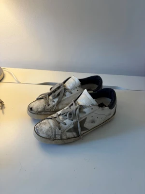 Golden goose skor - Säljer nu dessa slitna golden goose skor till den som känner sig manad för ett tvätt projekt! Själv har jag inte prövat tvätta dem alls utan lägger bara ut annonsen så här så att den som känner att den kan fixa upp dem får köpa dem. Annars i bra skick, de har den vanliga golden goose slitningen i klacken samt en slitning längst fram på ena skon. Sätter priset baserat på skicket men ingen är hugget i sten! Först till kvarn!👍
