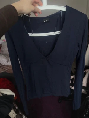 Mörkblå och Svart långärmad v-ringad topp (säljer båda för 150kr!) - Två stilrena mörkblå och svart toppar från Gina Tricot med lång ärm och djup v-ringning. Topparna har en enkel, figurnära passform och är tillverkad i ett mjukt material som känns bekvämt mot huden. Perfekt att matcha med jeans eller kjol för en clean look.