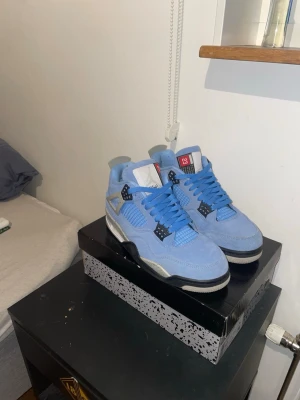 Jordan 4 University Blue sneakers - Säljer ett par Jordan 4 University Blue sneakers i ljusblå mocka med svarta och grå detaljer. Boxen som följer med är för ett par andra Jordan 4 men ser likadan ut för alla Jordan 4. Hör av dig vid minsta fråga elle fundering. Priset är inte spikat.
