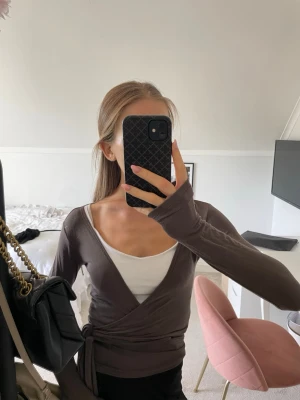 Brun omlottopp med knyte - Säljer en brun omlottopp med knyt i midjan och långa ärmar. 
