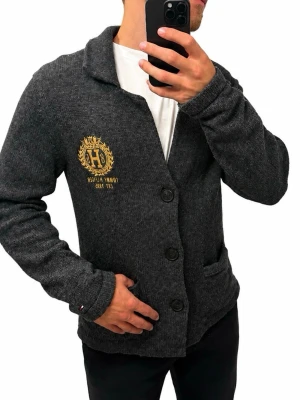 Tommy Hilfiger stickad cardigan  - Tommy Hilfiger stickad cardigan i mörkgrått.  Storlek: L Modellen på bilden är 186 cm lång.  Nypris uppskattningsvis ca 1 500–2 000 kr.  #TommyHilfiger #Tommy #Cardigan #StickadTröja #Herrmode #Menswear #Preppy #Premium #Höstmode #Vintermode