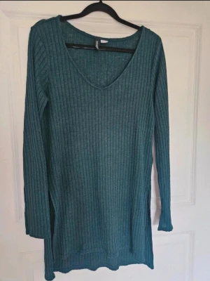 Tröja Tunika H&M Divided S - Snygg mörkgrön ribbad tröja från H&M Divided i storlek S. Tröjan har v-ringad hals, långärmade ärmar och slitsar i sidorna. Materialet är mjukt och stickat, perfekt för dig som gillar enkel och stilren look.  Kan även hämtas I Partille  E1