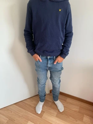 Tiger of Sweden Jeans - Säljer ett par ljusblå slim fit jeans med klassisk femficksdesign och normalhög midja. Storlek W27/L32. Jeansen har en snygg tvätt och smal passform som sitter tajt längs benen. Perfekta för en avslappnad och trendig stil.