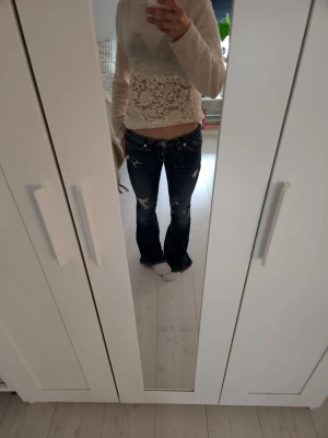 RESERVERAD! Mörkblå bootcut jeans med låg midja - RESERVERAD! Säljer ett par mörkblå bootcut jeans med slitna detaljer och låg midja. Jeansen har klassiska fem fickor och snygga slitningar på låren och knäna för en trendig look. Knappt använda och inga defekter, skriv för mer bilder