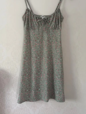 Sommarfin klänning - Sommar klänning, kort. Grön med rosa/vita blommor. Axelband. Polyester 95% och elastan 5%