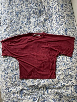 Vinröd t-shirt  - Säljer en vinröd t-shirt från 157 (som inte finns kvar på hemsidan) med korta ärmar och rund hals. T-shirten sitter tajtare i midjan och lösare vid armarna och är perfekt för en chill och avslappnad stil. Använd endast ett par fåtal gånger.