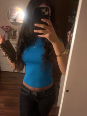 Tight blå crop top med kort ärm - Säljer en tight, blå crop top med korta ärmar. Toppen har en enkel och stilren design som sitter figurnära och framhäver midjan. Perfekt att matcha med jeans eller kjol för en trendig look.