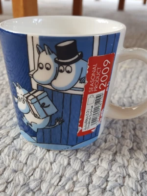 Muminmugg Julöverraskning Mumin  - Felfri mugg men etiketten är skadad. Säljer fler Muminmuggar så kika gärna på mina övriga annonser också. Packar mycket noggrant. 
