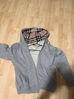 Grå hoodie med rutigt foder i huvan - Säljer Dena helt nya burberry koftan helt ny och inga problem saknar kvitto till Dena .