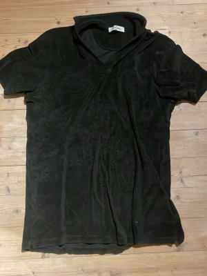 Svart t-shirt i frotté från Gran Sasso - Säljer en svart t-shirt från Gran Sasso i mjuk frotté. T-shirten har korta ärmar och en klassisk passform. Perfekt för dig som gillar en unik och bekväm stil. Enkel att matcha med jeans eller shorts.