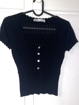 Zara topp  - Svart topp med broderier typ från Zara med vita knappar och liten knytning längst fram i storlek S 