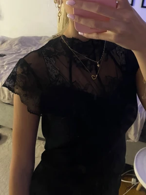 Svart spets tröja - Snygg svart från missäy/by clara paris tröja med transparent spets upptill och korta ärmar. Hög hals och figurnära passform. Perfekt för dig som gillar en elegant och stilren look med fina spetsdetaljer. Liten i storlek men stretchig så passar både s m och xs. Köpt för 299💞