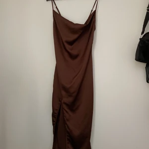 Brun klänning med slits - Superfin brun tight klänning med slits. Köptes på Plick men var tyvärr för liten eftersom jag är en 36a. Klänningen är i 100% polyester och har en satinliknande känsla. Tunn och smiter åt jättesnyggt runt midja och höft. Går till knäna på mig som är 175 cm. FRAKT INGÅR I PRISET!