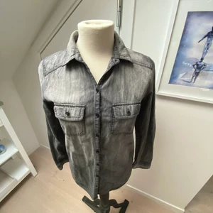Grå jeansskjorta  - Snygg grå jeansskjorta med svarta knappar! Den ska sitta rätt tajt och passar dig som har storlel XS eller S. 😎 
