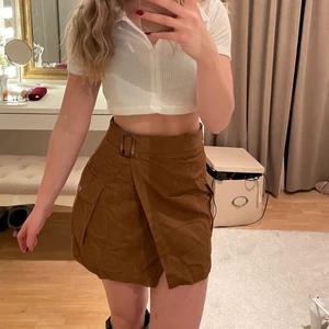 Mocka kjol  -  Jättesnygg kort kjol i mocka imitation från Nastygal! Används sparsamt! Kjolen är omlott! Passar perfekt nu till höst och vinter med ett par höga boots och en kofta! Storlek 36 men skulle säga att det är mer en 34! Nypris ca 300 kr! Köparen står för frakten ❤️