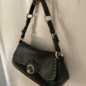 Vintage väska - Den har lite slitningar och avskavd färg på vissa detaljer på framsidan. Köpt: på humana. Märke: okänt. Färg: svart läder med silver detaljer. Storlek: va 30cm lång, 12 cm hög, 10 cm bred. 