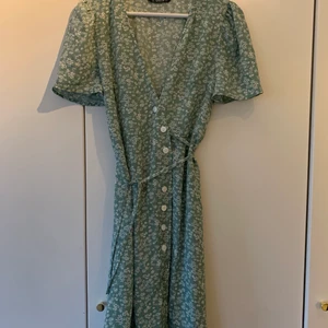 Klänning  - Ljusgrön klänning med vita blommor. Storlek L men mer som en M. 